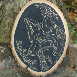 A fox surrounded by flowers carved into wood.