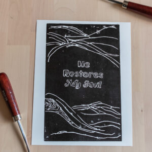A print of swirling lines surrounding the words, "He Restores My Soul".