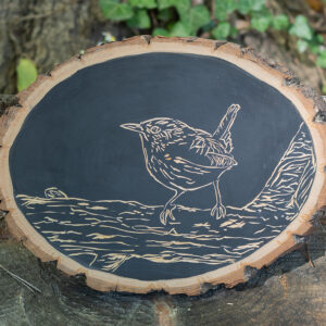 A wren perched on a branch carved into wood.